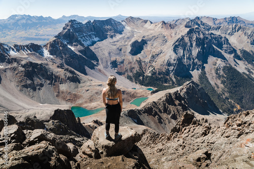 A woman standing at the summit of Mount Sneffles enjoying the view of the Blue Lakes.  photo