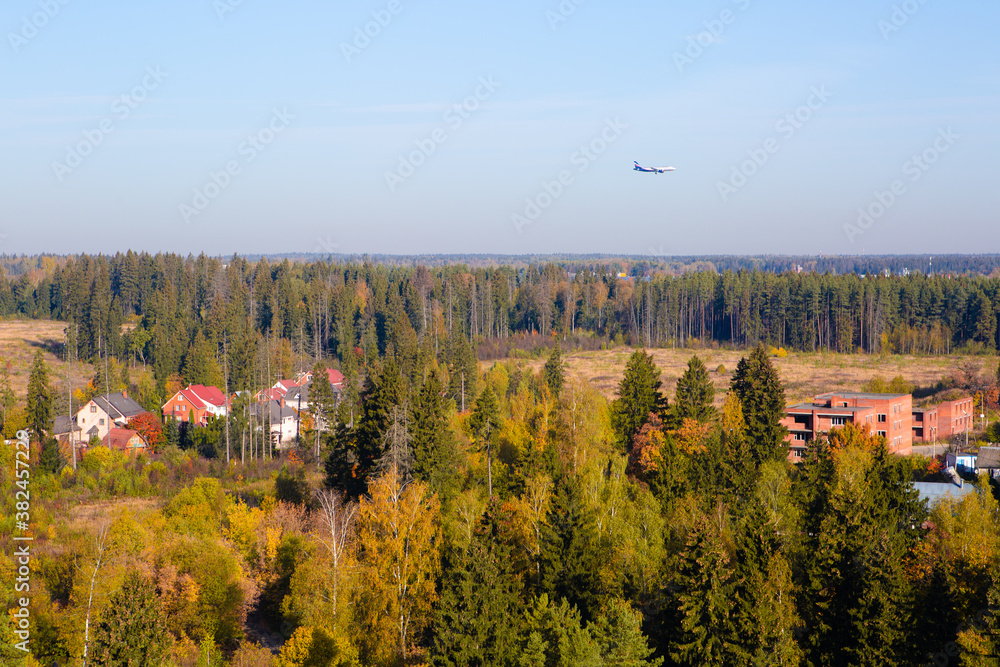 The plane is flying over the village