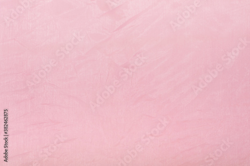 Background of pink paper covered with artificial transparent silk, fabric.