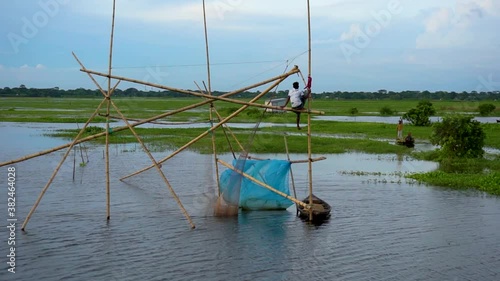 Fishermen are fishing in the bill or lake with big nets. Traditional village fishing in Bangladesh. photo