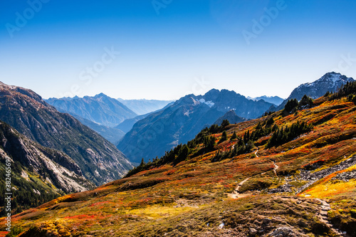 Fall foliage in bloom across mountain valleys with snow capped mountain peaks in the background