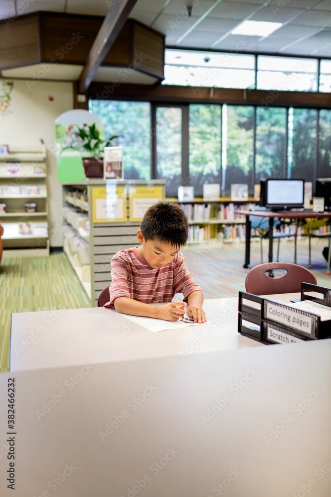 Asian kid studying in a public library Asian kid studying in a public library