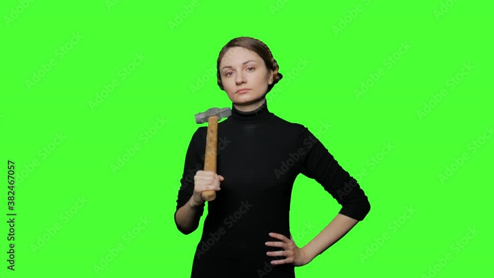 serious woman looks with a stern look and holds a hammer in her hand serious woman looks with a stern look and holds a hammer in her hand