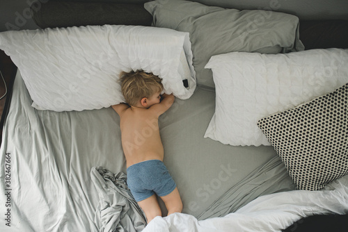 Boy napping in parent's bed in boxer briefs photo