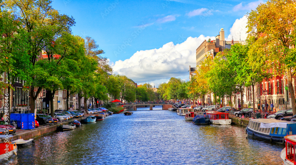 classical and traditional view of Amsterdam canals at summer time with boats and old architecture of the capital of the Netherlands