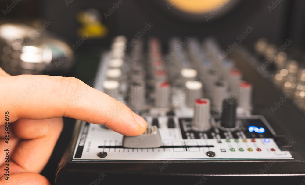 Sound engineer using main control fader of studio mixer. Sound engineer using main control fader of studio mixer.