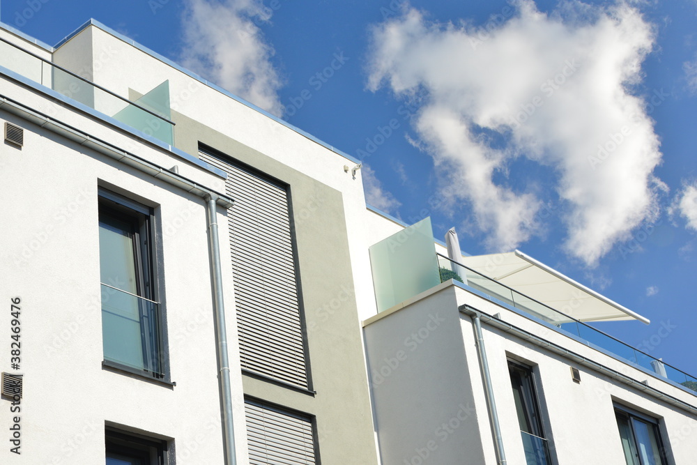 Verglaster Balkon mit Edelstahl-Geländer, Edelstahl-Kasten-Dachrinnen und Milchglas-Sichtschutz an der Fassade eines modernen Flachdach-Mehrfamilienhauses