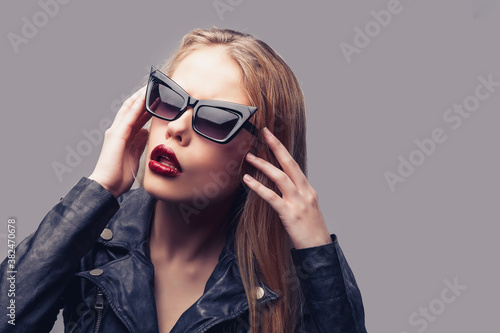 Fashion portrait of young elegant woman in black leather jacket, sunglasses.