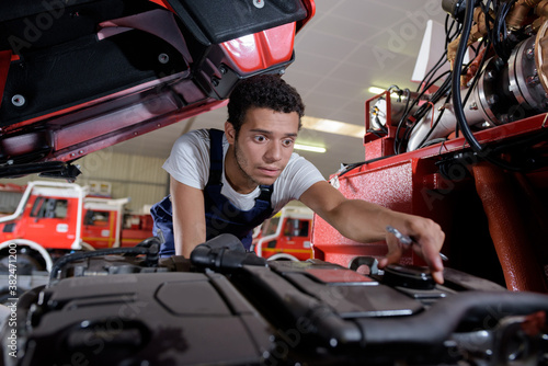 young male car mechanic with wrench in garage