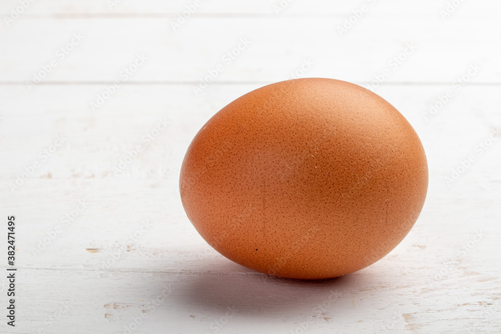 a brown egg on a white wooden background a brown egg on a white wooden background