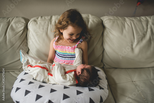 girl smiling at newborn baby photo