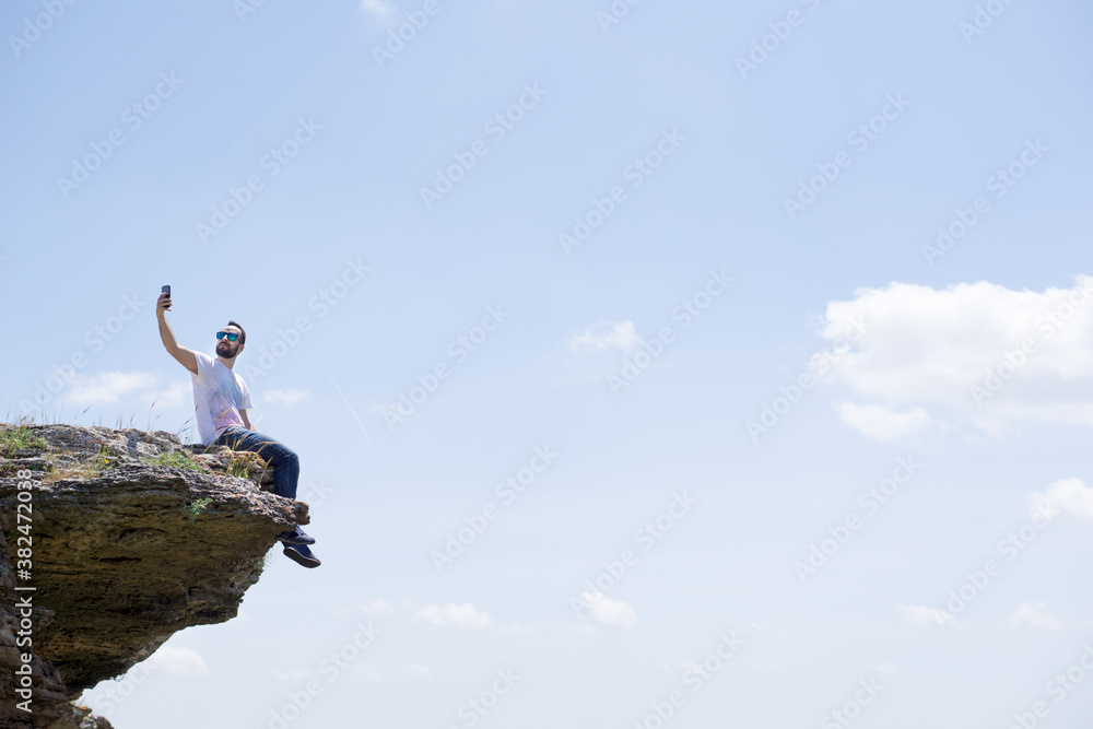 Young man taking a selfie on a high rock Young man taking a selfie on a high rock