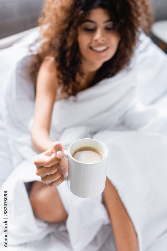 selective focus of curly woman looking at cup of coffee in morning selective focus of curly woman looking at cup of coffee in morning