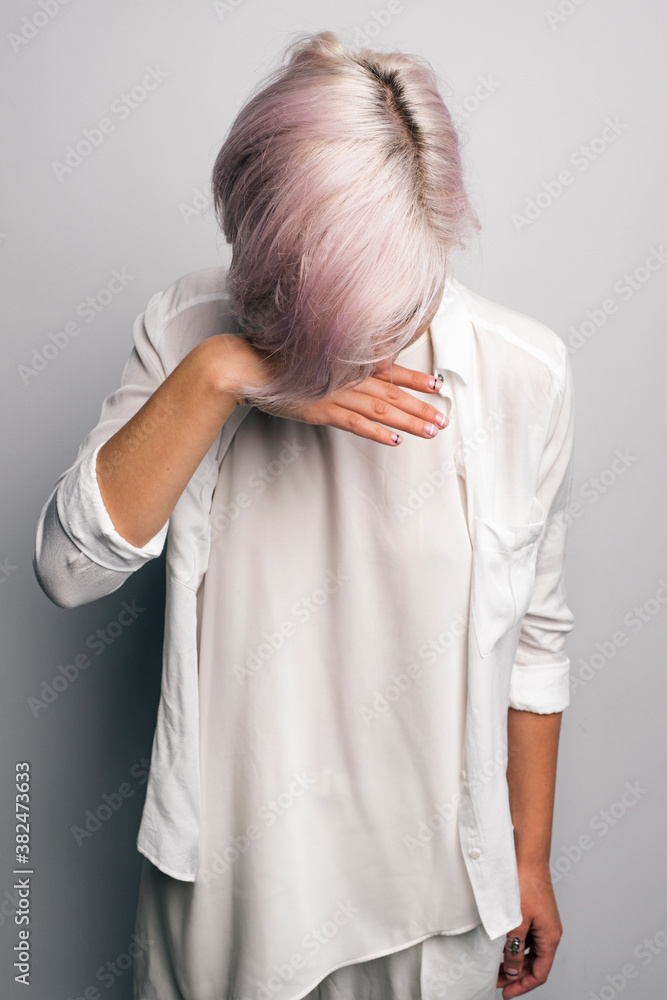 Young girl with pink hair looking down wit hand near face Young girl with pink hair looking down wit hand near face