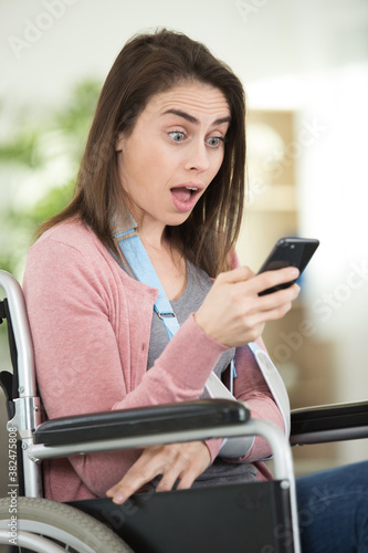 surprised woman on wheelchair looking at her mobile