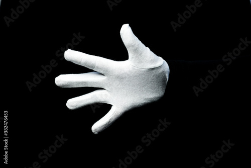 A hand wearing white glove on black background counting down
