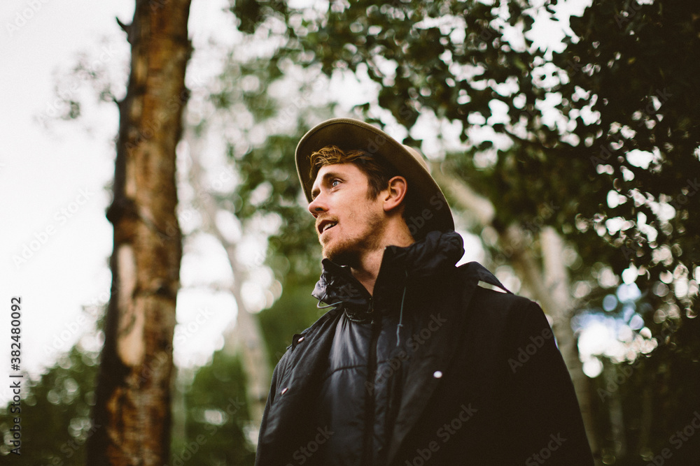 One man in black jacket gazes into distance in forest One man in black jacket gazes into distance in forest