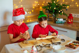 Happy children are preparing gingerbread on the eve of new year. Boy and girl in the kitchen waiting for Christmas. Children make holiday cookies at home. Family traditions on Christmas Eve