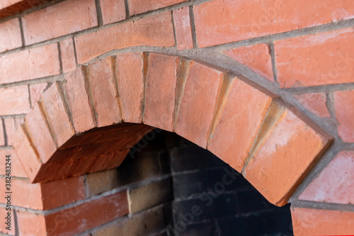 fireplace new built of red brick with arched firebox close-up heating the house