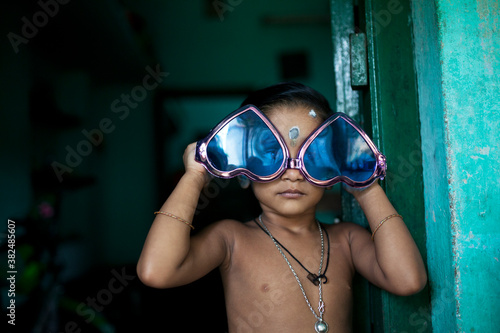 A kid with fashionable blue color spectacles with love sign shape photo