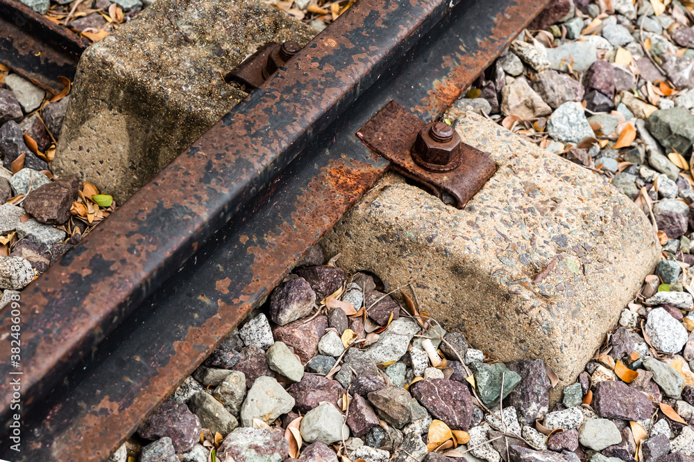 old rusty rail bolted to the cement sleeper close-up on a background of gravel part of the way old rusty rail bolted to the cement sleeper close-up on a background of gravel part of the way