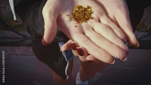 A girl is blowig out golden particles away from her palm slow motion shot photo