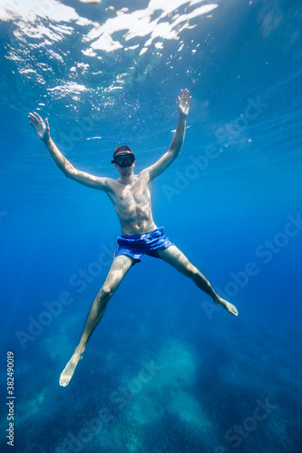 Wallpaper Mural Young man in a blue shorts floating submerged in the Meditterane Torontodigital.ca