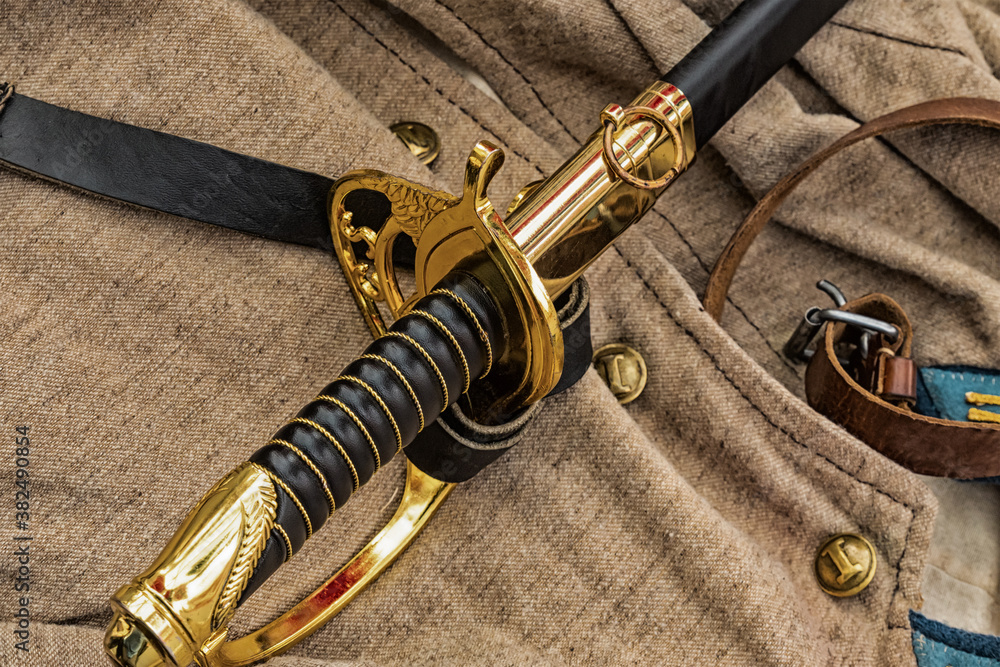 Naklejka premium the sword is black the golden handle of the civil war of 1861-1865 lies against the background of the traditional soldier uniform, jacket and leather belt