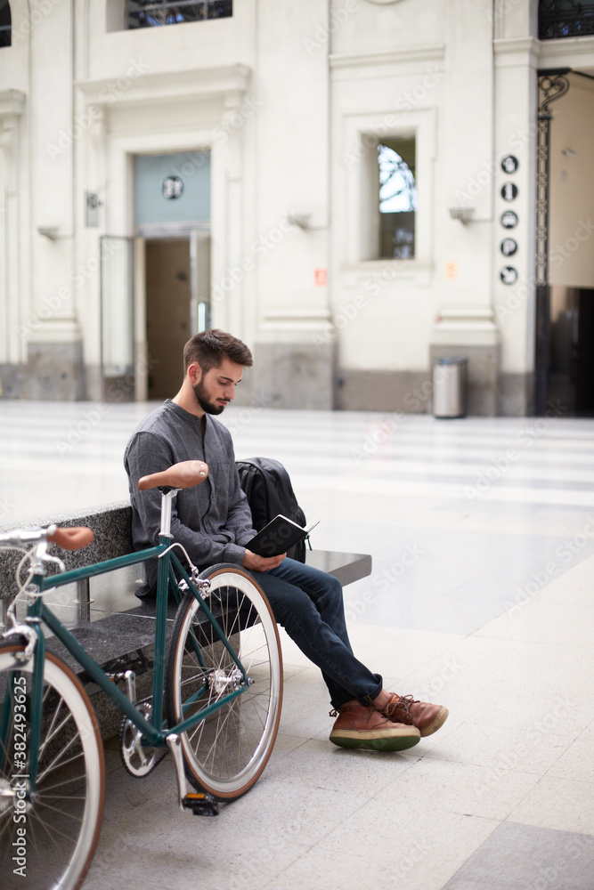 Young man sitting in the railway station and reading a notebook Young man sitting in the railway station and reading a notebook