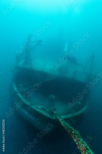 Scuba diver exploring the shipwreck deep under the sea photo