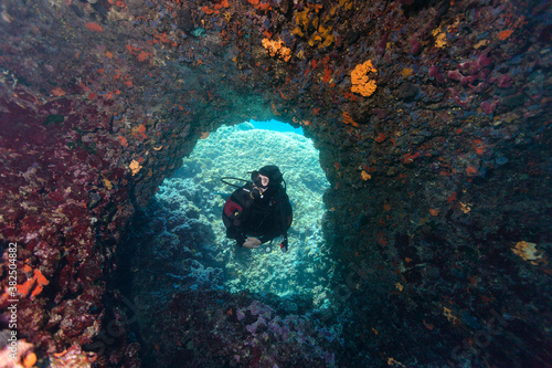 Scuba Diver admiring corals that covered underwater swim trough photo