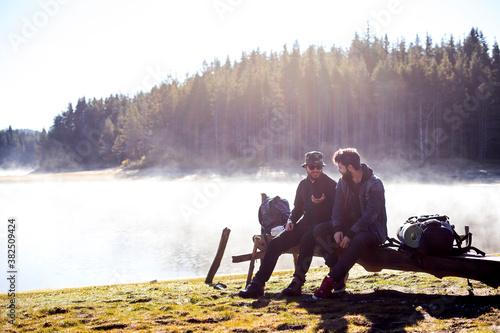 Friends sitting on a dock near a lake