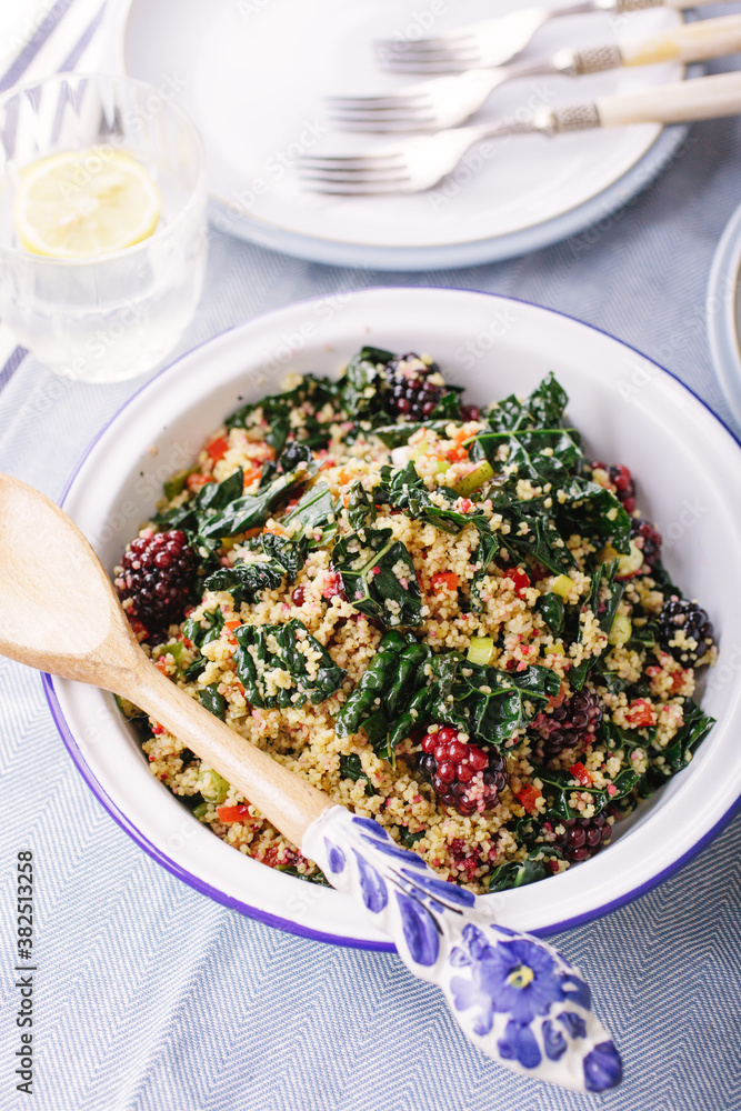 Side view of a bowl of kale salad with couscous and fruit. Side view of a bowl of kale salad with couscous and fruit.