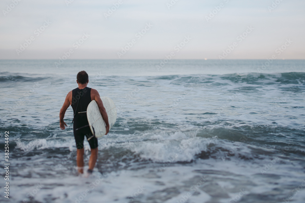 Mature surfer man heading into the water Mature surfer man heading into the water