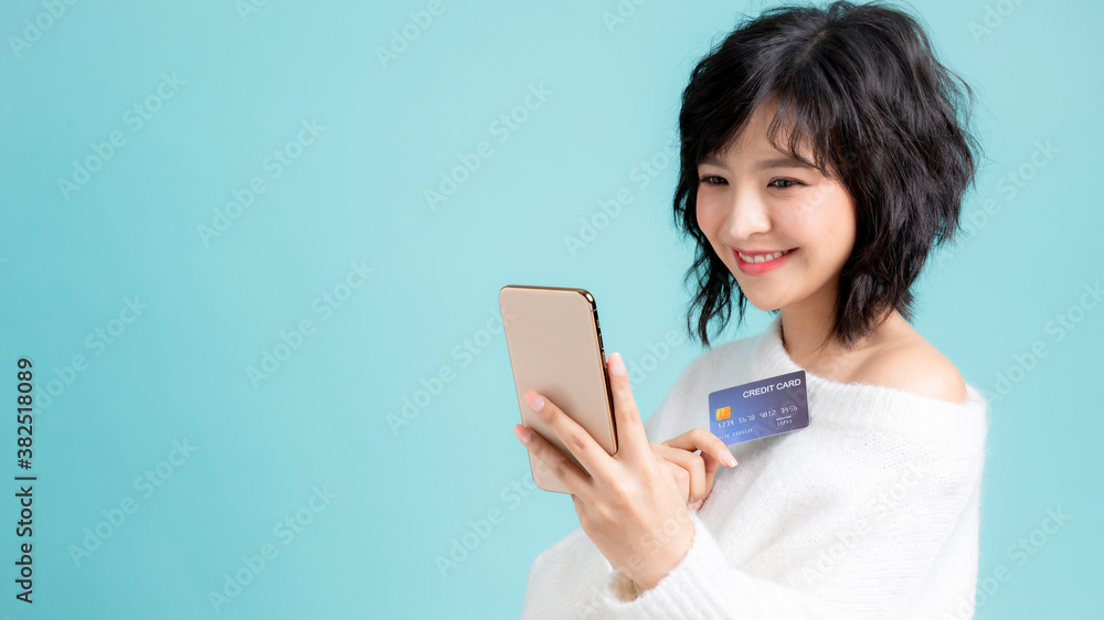 Portrait of young woman holding a credit card and mobile phone Portrait of young woman holding a credit card and mobile phone