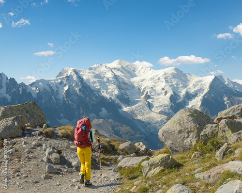 Woman carrying large backpack trekking in Mont Blanc massiff photo
