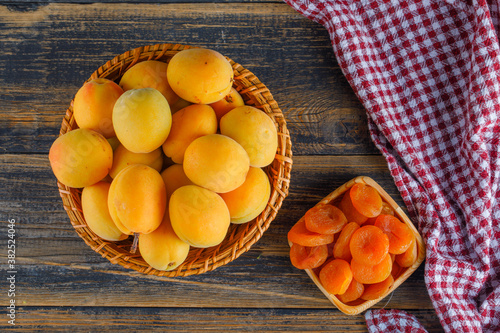 Apricots in a wicker basket with dried apricots flat lay on picnic cloth and wooden background
