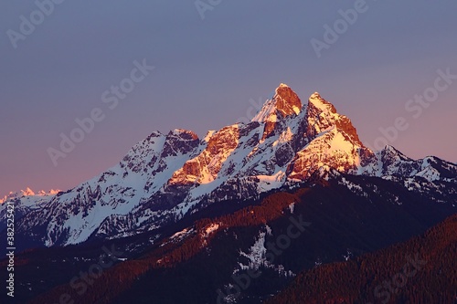 Canadian and American Border Peak Mountain covered in snow with last sun rays during red sunset in winter, British Columbia, Canada