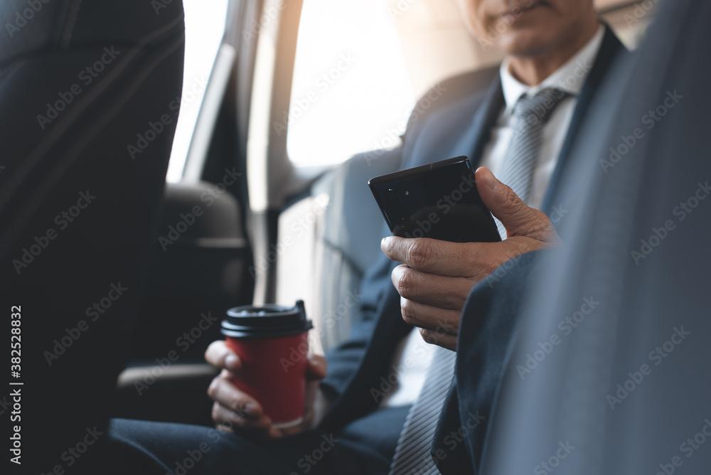 Businessman inside a car using mobile smart phone and drinking coffee going to workplace with morning light Businessman inside a car using mobile smart phone and drinking coffee going to workplace with morning light