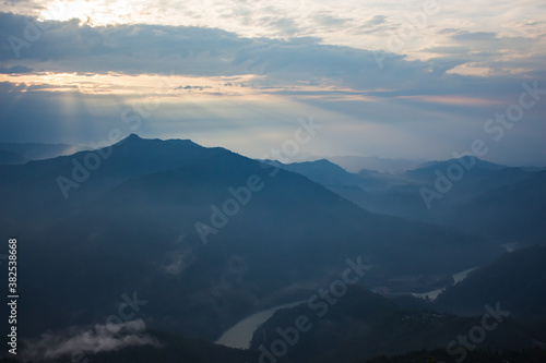 beautiful landscape of hills silhouette during sunrise. light breaking through cloud cover. © suparna