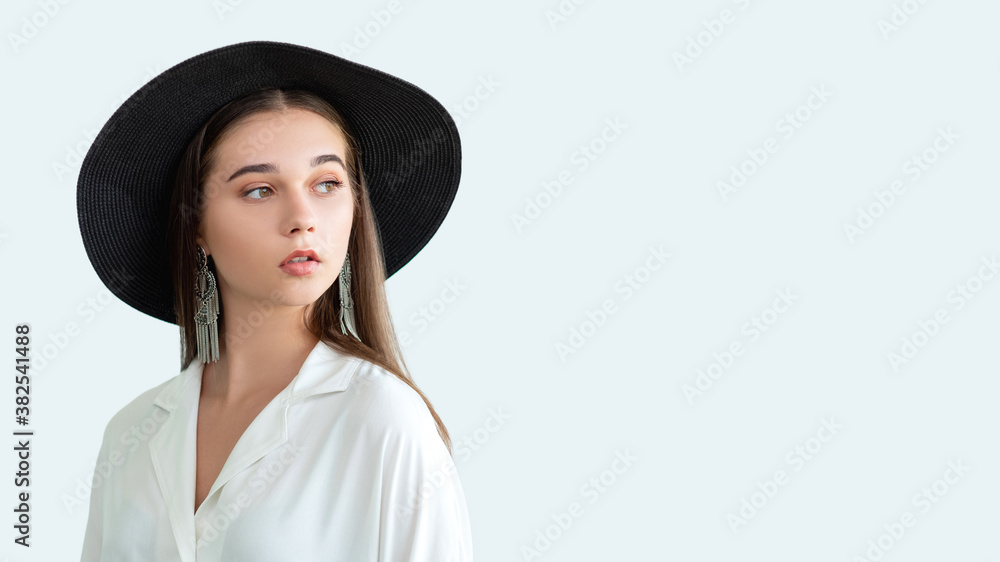 Summer fashion look. Boho style. Beautiful woman in straw black hat vintage earrings white shirt isolated on neutral copy space. Hipster lifestyle. Female elegance. Advertising background Summer fashion look. Boho style. Beautiful woman in straw black hat vintage earrings white shirt isolated on neutral copy space. Hipster lifestyle. Female elegance. Advertising background