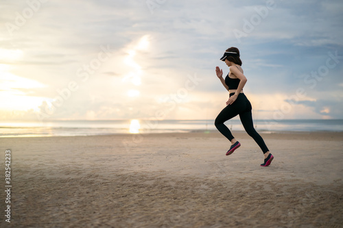 Side view of woman jogging on beach in the morning.