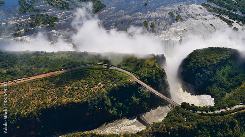 Stunning aerial panorama view of the majestic and powerful Victoria Falls (largest waterfall worldwide) with historic bridge at the border of Zimbabwe and Zambia, Africa.
