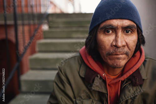 Portrait of older, native homeless man siting on steps
