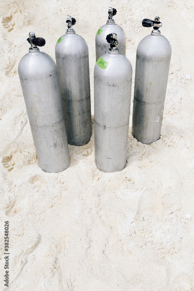 Five aluminum, air scuba diving tanks on the sandy beach Five aluminum, air scuba diving tanks on the sandy beach