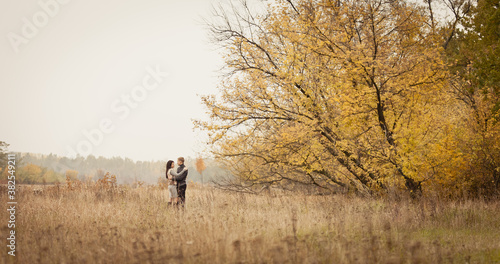 couple on autumn walk outdoors. Two lovers in autumn park. Love and tender touch. Foggy cloudy day filled with the warmth of love. Beautiful autumn landscape for couple