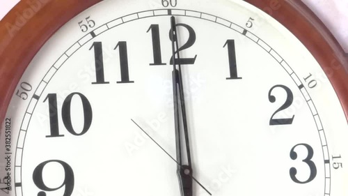 Close-up of a vintage clock face at 12 o'clock with a second hand moving photo