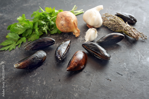 Ingredients for a seafood dish with mussels, onion, garlic, parsley and dried herbs on a grey slate, copy space, selected focus