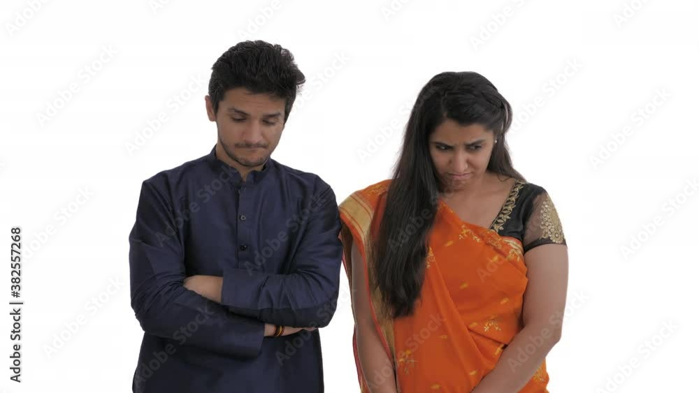 Young Indian couple looking down with a guilty look. Body language and human emotions concept. Isolated on white background Young Indian couple looking down with a guilty look. Body language and human emotions concept. Isolated on white background
