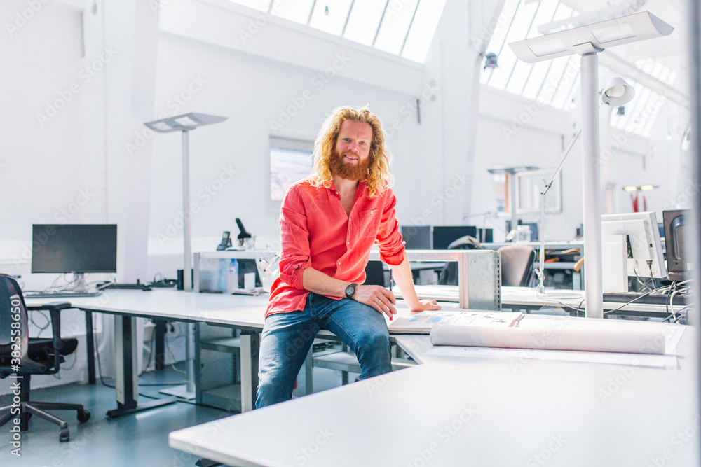 Young designer sitting on a table working on his designs Young designer sitting on a table working on his designs